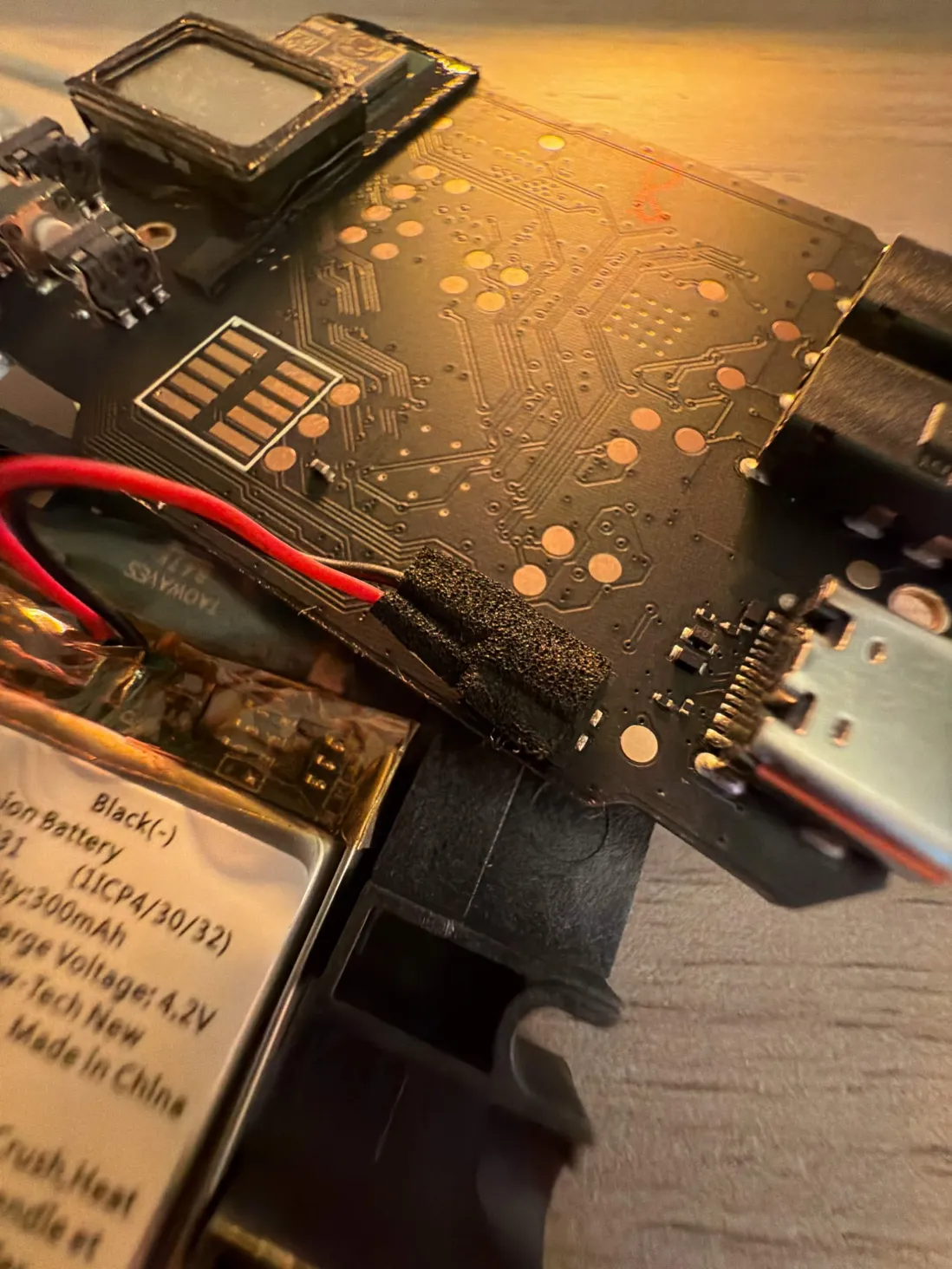 The battery connector hidden under black foam tape