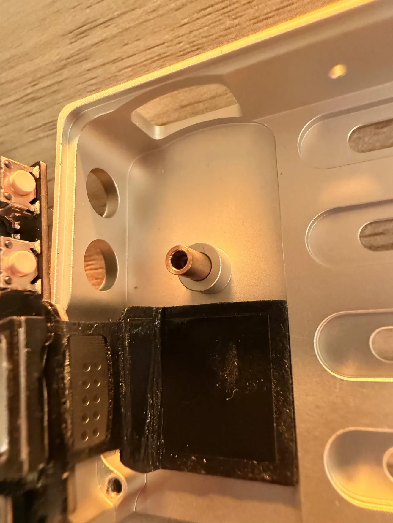 Inside the case: the copper rocker bushing standing up, and the black acoustic rubber gasket below it